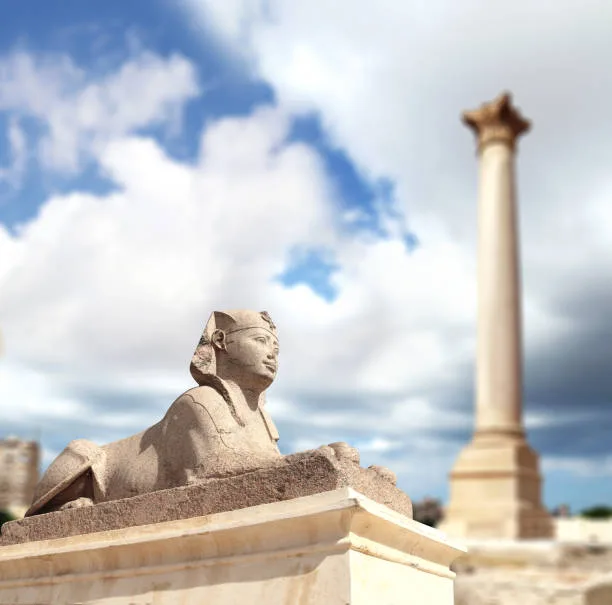 Ancient sphinx statue and Pompey's Pillar at archaeological site in Alexandria Egypt