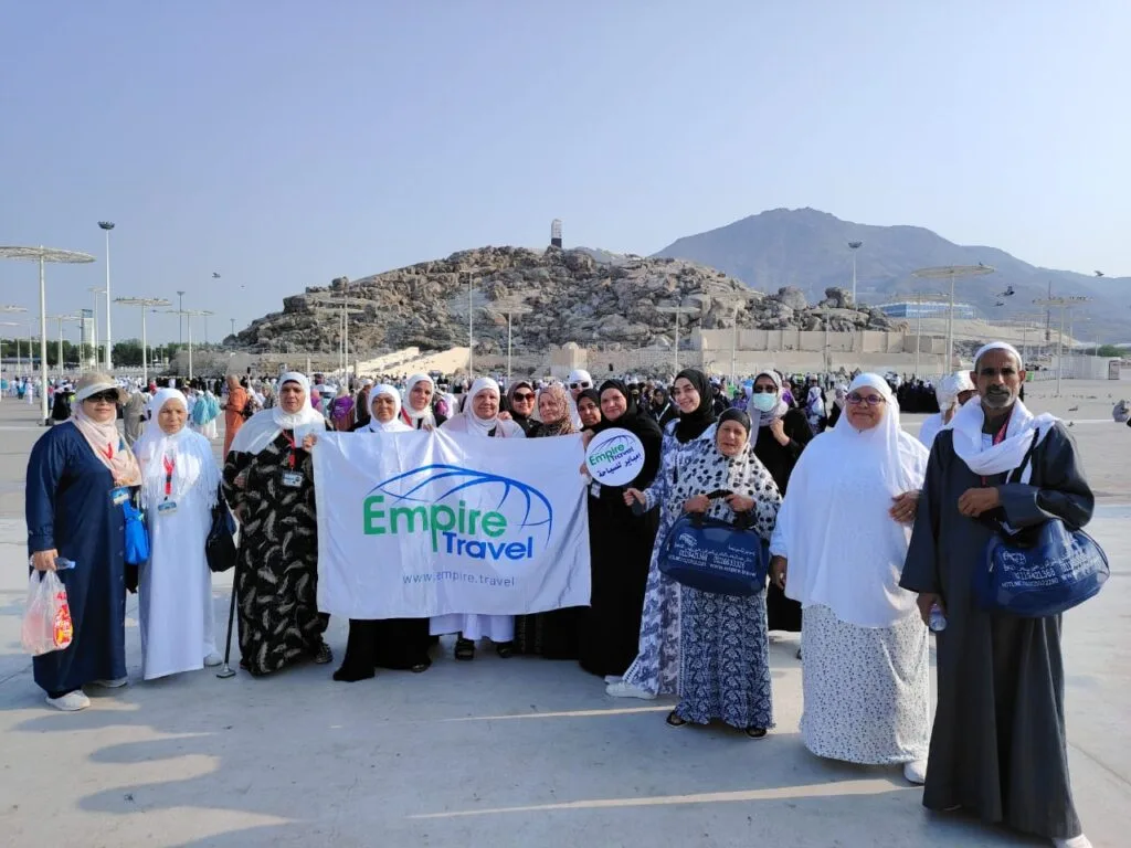 Empire Travel pilgrims group holding company banner at Mount Arafat during Hajj pilgrimage in Saudi Arabia