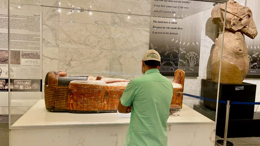 Empire Travel tourist examining ancient Egyptian sarcophagus with hieroglyphics at National Museum of Egyptian Civilization Cairo