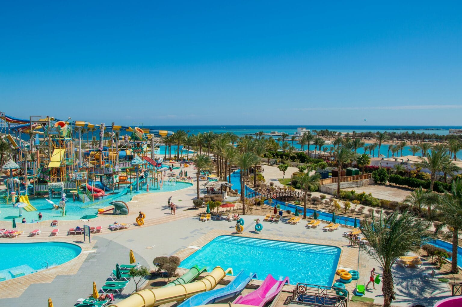 Beach resort in Hurghada Egypt featuring water slides, swimming pools, palm trees, and views of the Red Sea coastline.