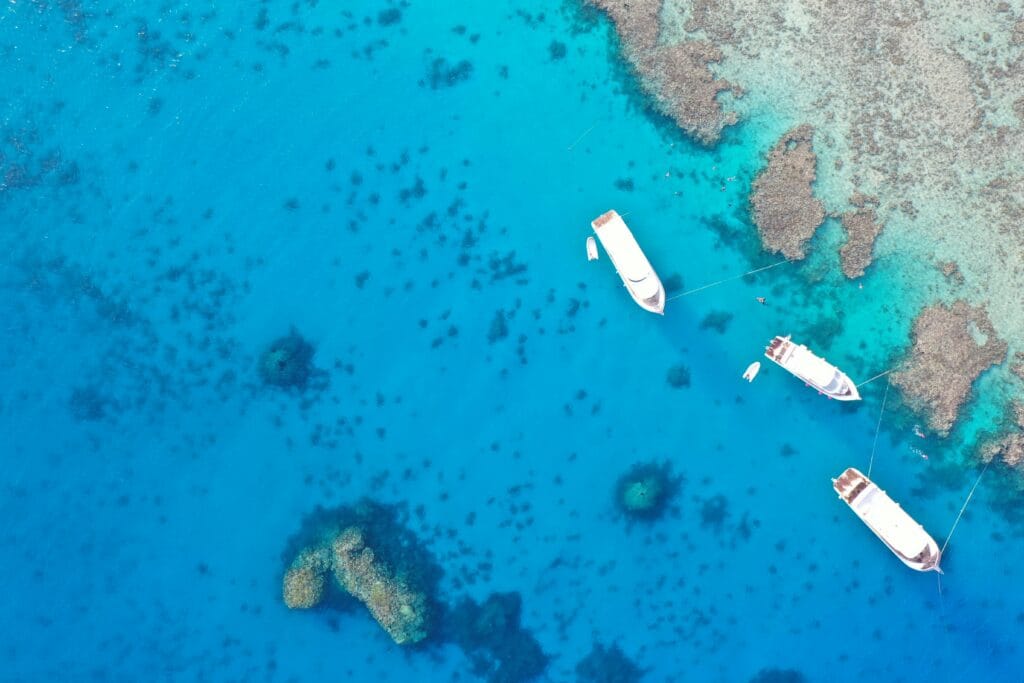 Aerial view of snorkeling boats above coral reefs in the clear turquoise waters of the Red Sea near Hurghada, Egypt.
